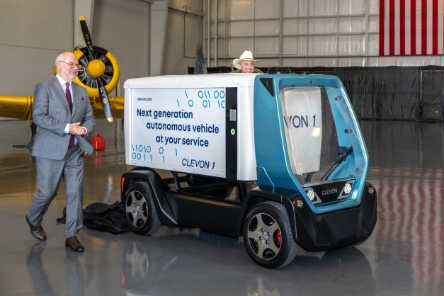 Estonian President Alan Karis walks alongside an autonomous delivery vehicle manufactured by Clevon.