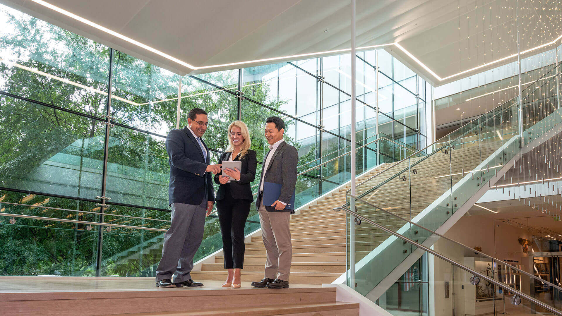 A woman and two men pause as they descend an office staircase.