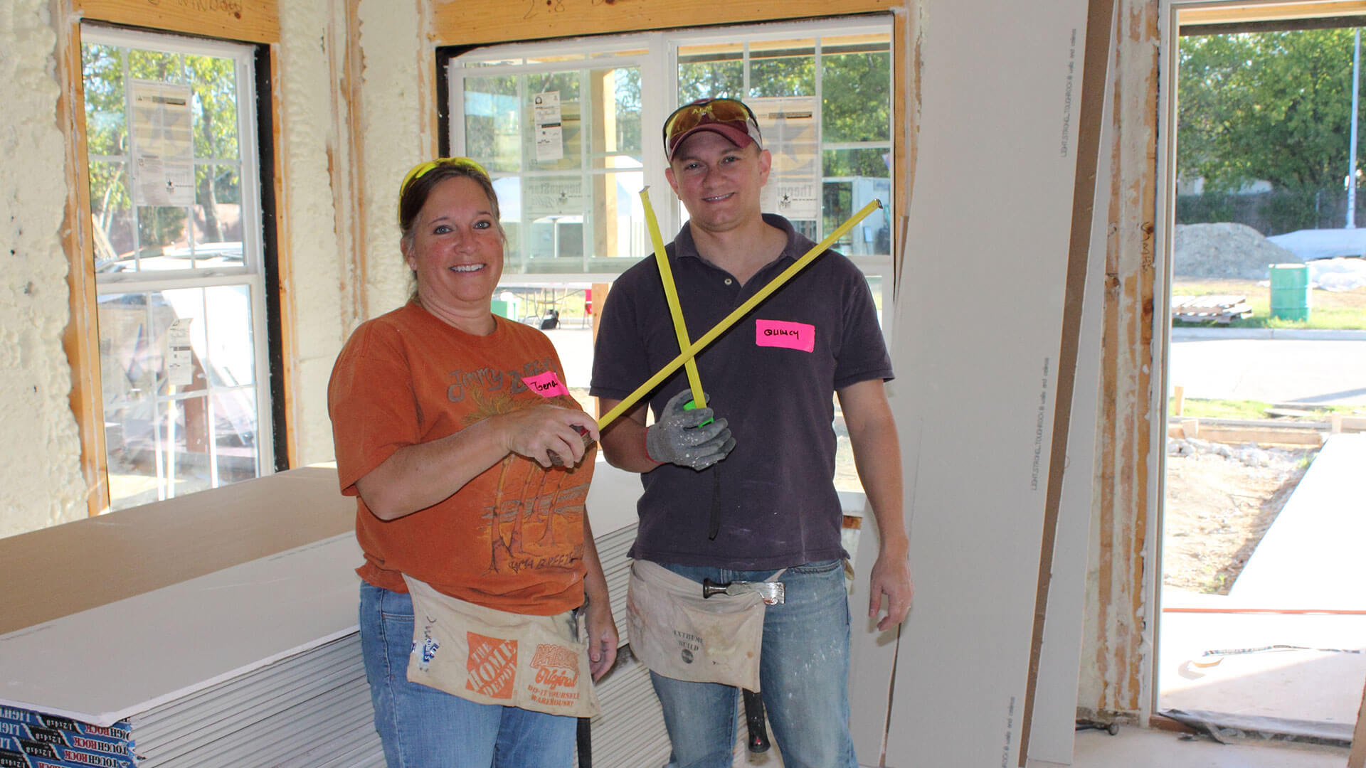 Two Hillwood employees show off their measuring tape skills at a Habitat for Humanity build.