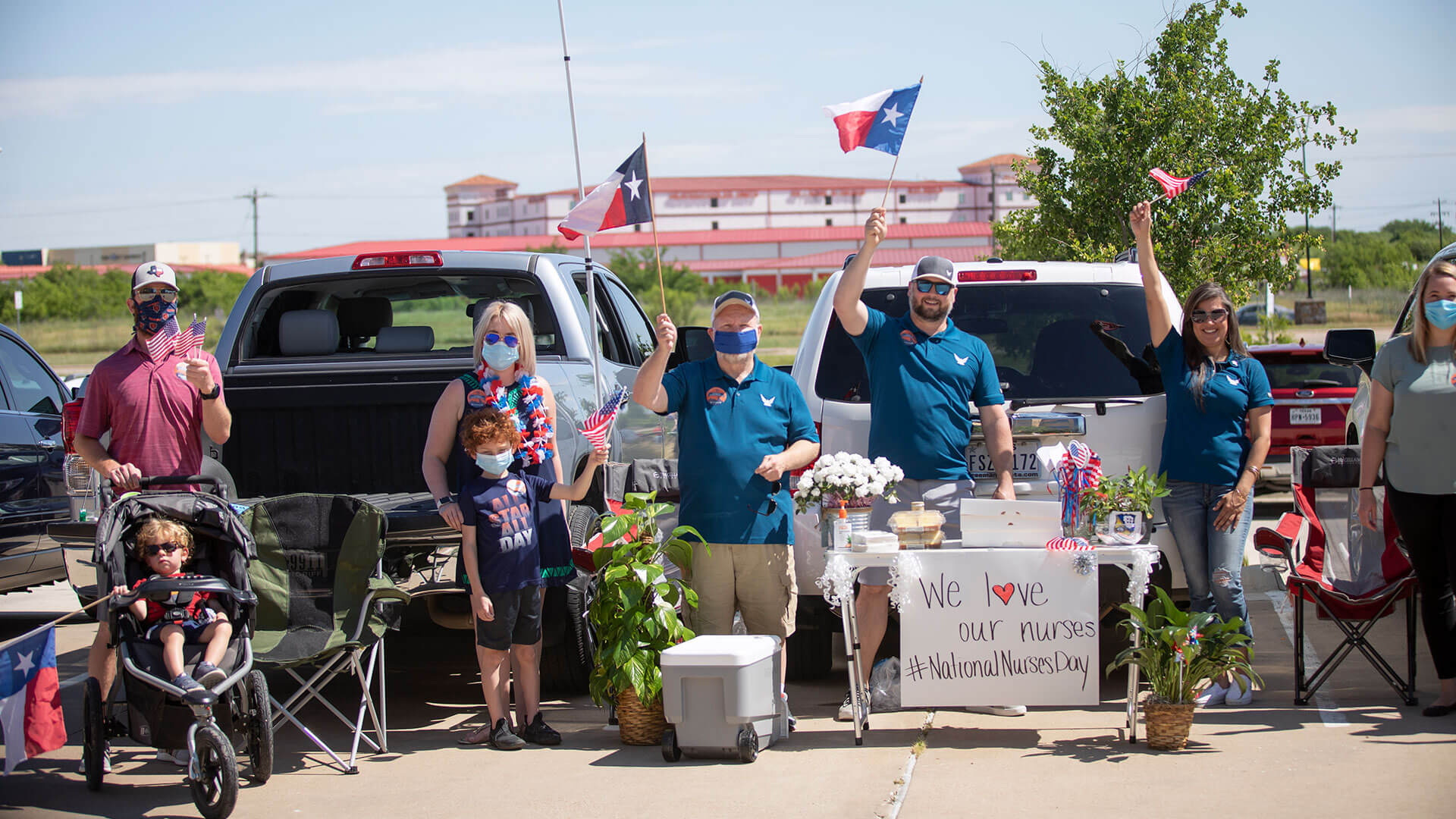 Two Hillwood employees wave Texas flags as they celebrate the contributions of healthcare workers.