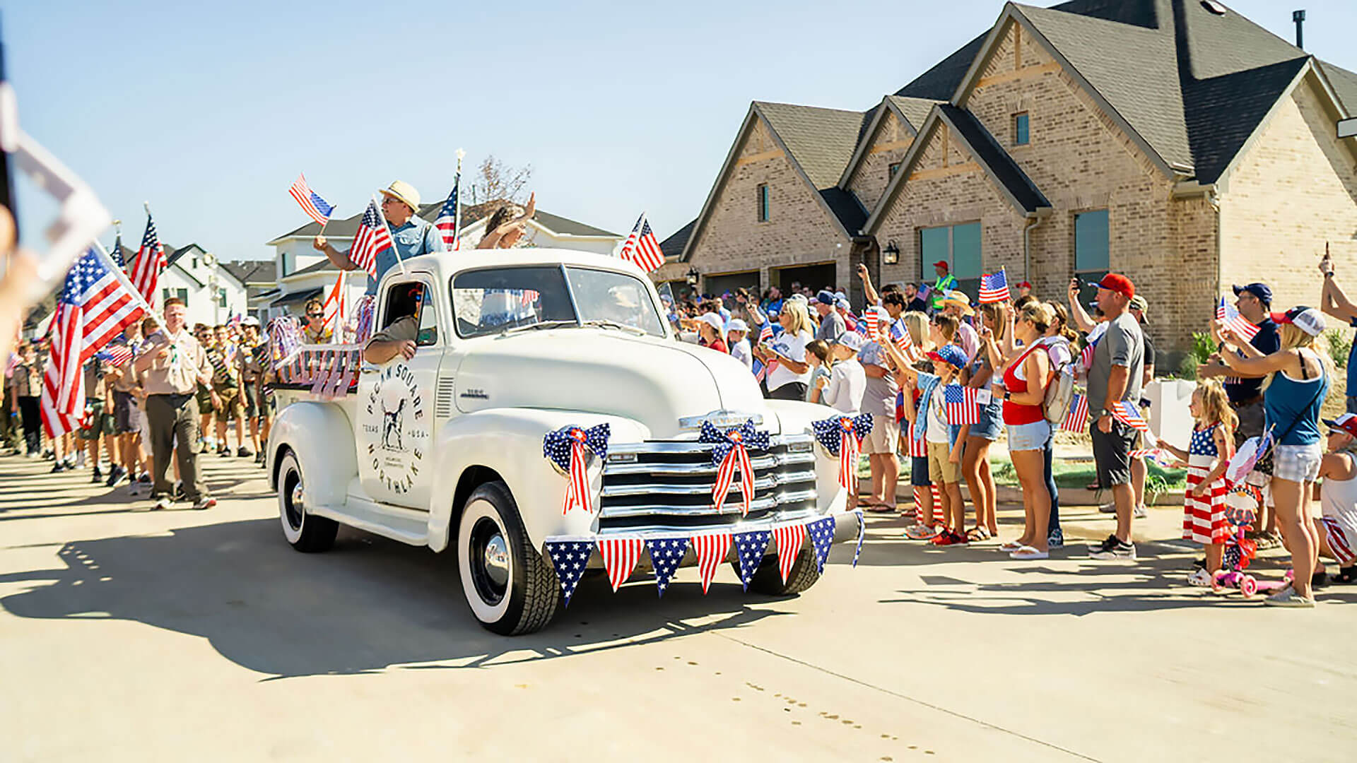 An American flag-covered truck is seen in a parade at Hillwood’s Pecan Square development in Northlake, Texas.