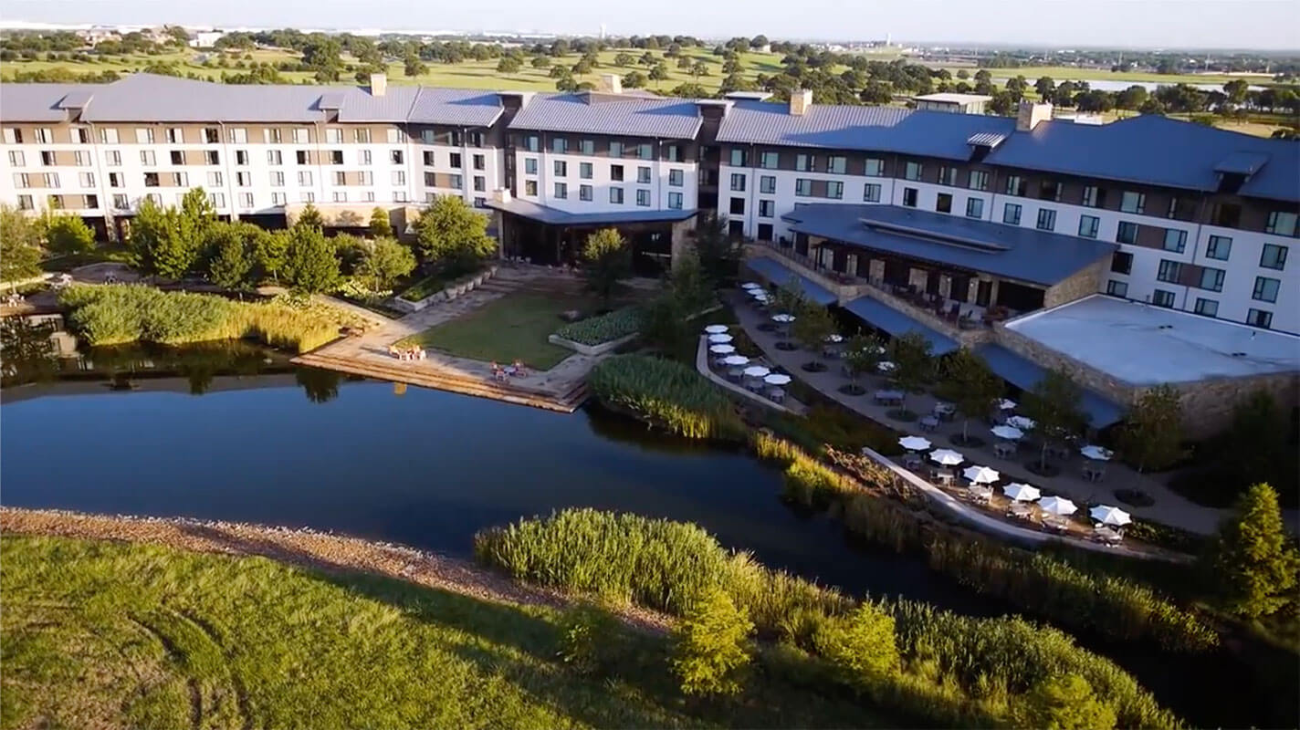 A row of multi-story buildings near a creek at a Hillwood-built Deloitte learning campus.