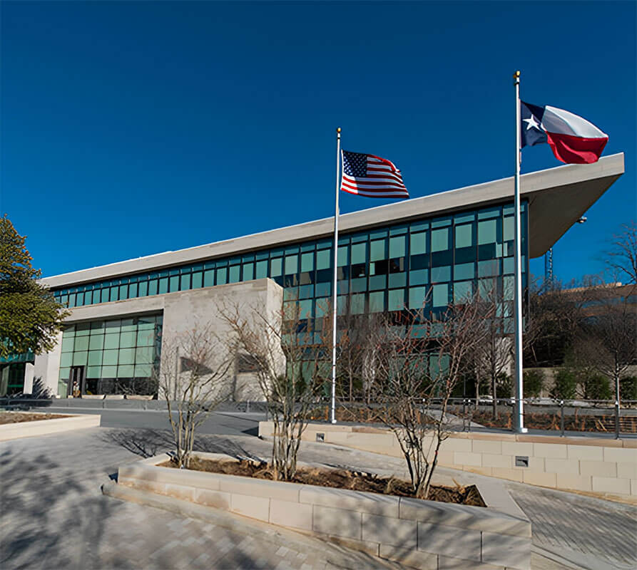 American and Texas flags fly in front of a glass building that is a new corporate office for Hillwood and The Perot Companies.