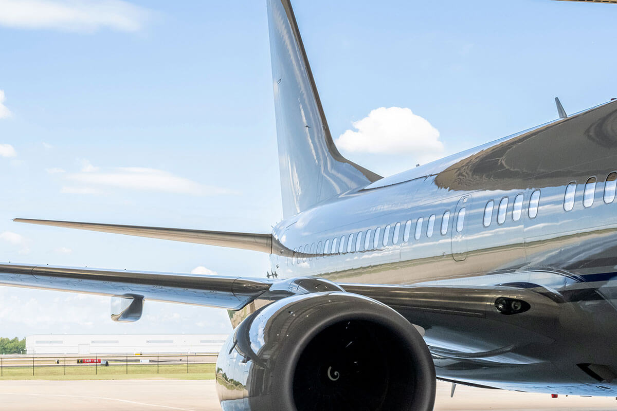 The rear of a jet — including engine, right wing and tail — that is parked on a tarmac.