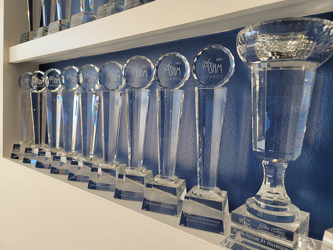 Two rows of glass trophies for the Dallas Builders Association People’s Choice Community of the Year Award.