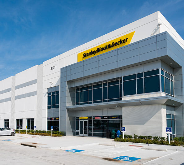 A white manufacturing plant is seen with a sign reading, 'StanleyBlack&Decker'