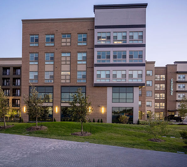 A brick and glass townhome building lights up at twilight.